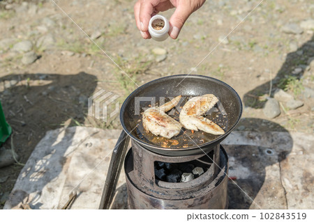 [Sprinkle outdoor spices while grilling chicken wings with embers] 102843519