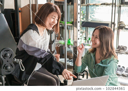 亞洲女性在健身房諮詢私人教練和訓練菜單 102844361