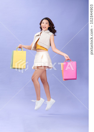 Image of laughing pretty young woman jumping isolated over purple background. 102844903