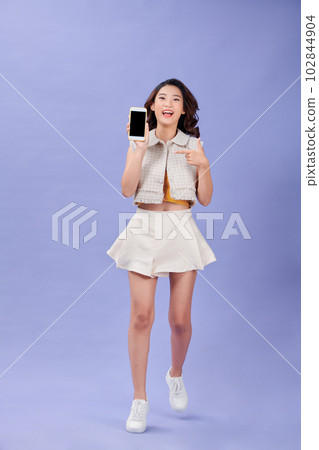 Young smiling attractive woman is pointing on blank screen of phone in her hand 102844904