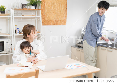 一對遠程工作的夫婦和一個模仿母親在智能手機上玩把戲的嬰兒之間的微笑對話 102844999