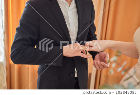 the bride in a dressing gown puts a wedding ring on her finger. 102845085