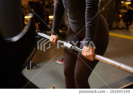 Close-up of a woman doing deadlift exercise alone at the gym. 102845149