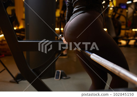 Close-up of a woman doing deadlift exercise alone at the gym. Close-up of a woman doing deadlift exercise alone at the gym. 102845150