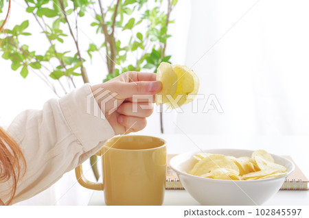 A woman eating potato chips 102845597