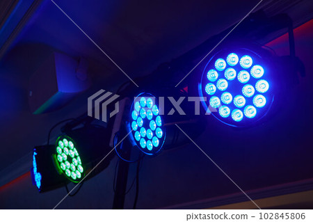 Installation of professional sound, light, video and stage equipment for a concert. Stage lighting equipment is clamped on a truss for lifting. Flight cases with cables. 102845806