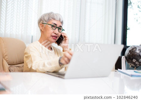 Asian senior business woman grey hair calling telephone sitting at office table. Asian senior business woman grey hair calling telephone sitting at office table. 102846240