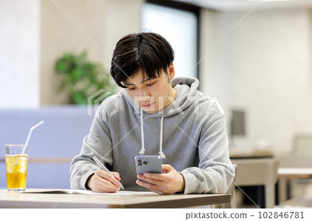 A student studying while looking at a smartphone in a cafe 102846781