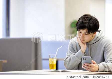 A student studying while looking at a smartphone in a cafe 102846785