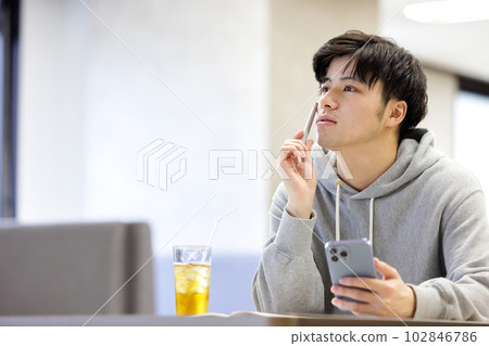A student studying while looking at a smartphone in a cafe 102846786