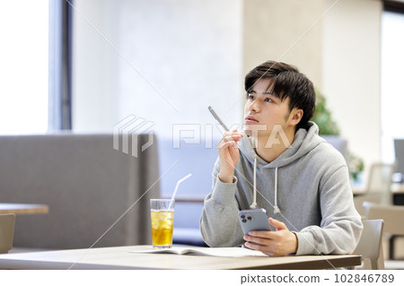 A student studying while looking at a smartphone in a cafe 102846789