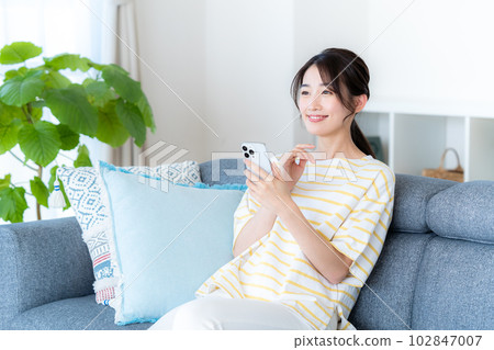 A young woman operating a smartphone in a room A young woman operating a smartphone in a room 102847007