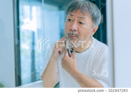 A middle-aged man taking care of his beard A middle-aged man taking care of his beard 102847265