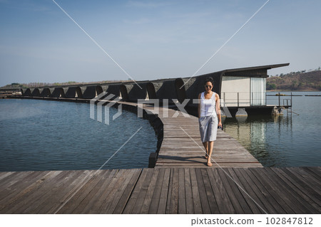 Serenity amidst luxury a woman walking on a resort's wooden floor. 102847812