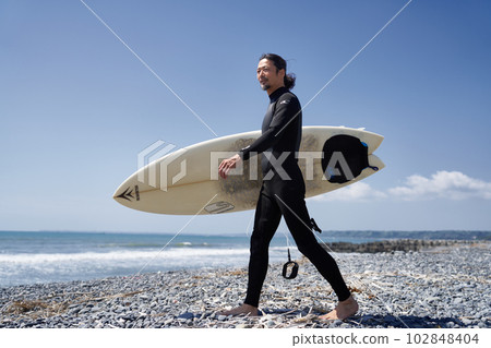 走在海灘的潛水服的中間男性衝浪者 102848404