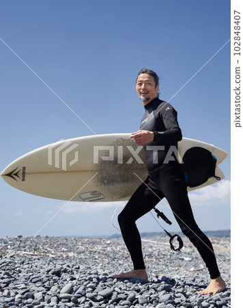 微笑著走在沙灘上的衝浪者的中間人 102848407