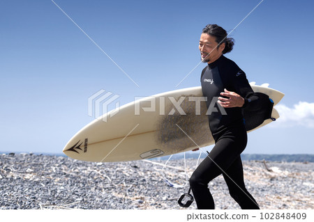 微笑著走在沙灘上的衝浪者的中間人 102848409