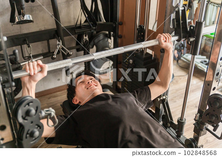 Man doing muscle training with bench press at gym Man doing muscle training with bench press at gym 102848568