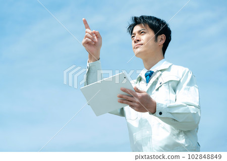 Businessman in work clothes with a tablet against the sky 102848849