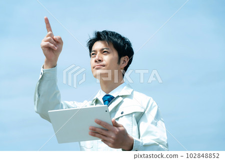 Businessman in work clothes with a tablet against the sky Businessman in work clothes with a tablet against the sky 102848852