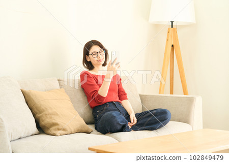 Young woman in plain clothes, living room, smartphone 102849479