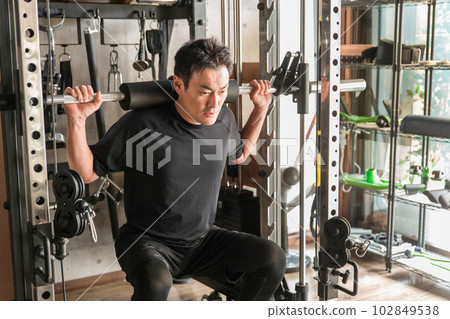 Asian man doing barbell squats in gym Asian man doing barbell squats in gym 102849538
