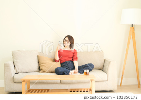 便衣的年輕女人，客廳，智能手機 102850172