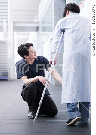 Image of rehabilitation and nursing care Crutches and a physical therapist supporting the patient Vertical 102850375
