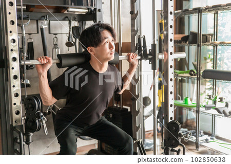 Asian man doing barbell squats in gym Asian man doing barbell squats in gym 102850638