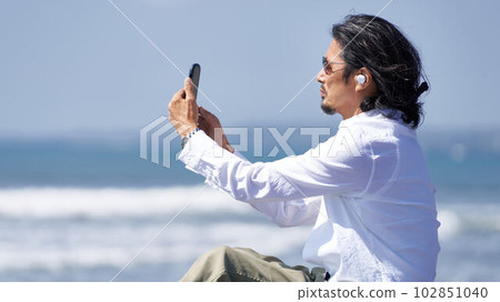 Middle man using a smartphone while watching the sea 102851040