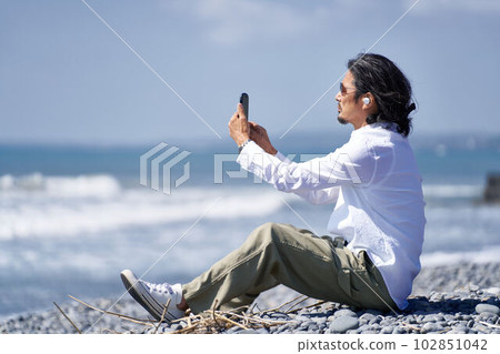 Middle man using a smartphone while watching the sea 102851042