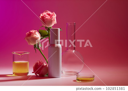 Front view in the laboratory with an empty label bottle decorated with Rose branches and some glassware. Copy space. The concept of beauty care products 102851381