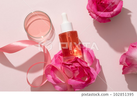 Natural skin care concept with pink liquid extracted from Rose (Rosa) contained inside a glass petri dish and a glass bottle with dropper. Branding mockup 102851395