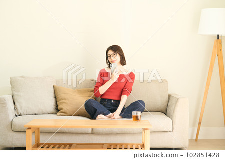 便衣的年輕女人，客廳，智能手機 102851428