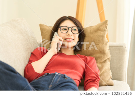 Young woman in plain clothes, living room, smartphone Young woman in plain clothes, living room, smartphone 102851436