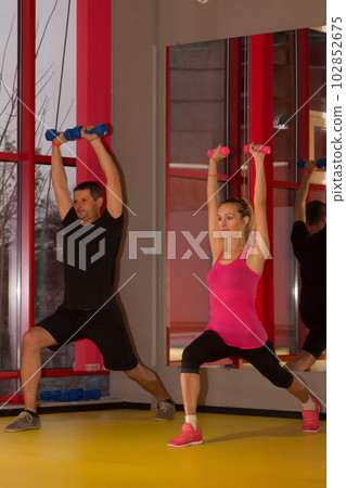 Woman and man exercising with dumbbells Woman and man exercising with dumbbells 102852675