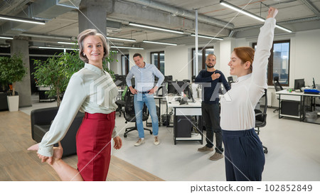 Four office workers warm up during a break. Employees do fitness exercises at the workplace. Four office workers warm up during a break. Employees do fitness exercises at the workplace. 102852849