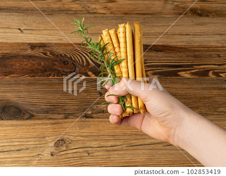 Bread Sticks in Hand, Salted Breadstick, Crispy Grissini, Dry Homemade Pretzels, Bread Stick on Wooden Background 102853419