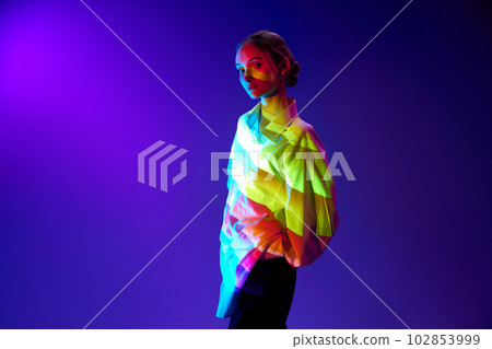 Portrait of beautiful, young girl with multicolored neon filter reflection on body, posing against purple background Portrait of beautiful, young girl with multicolored neon filter reflection on body, posing against purple background 102853999