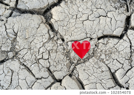 A little red paper heart on the land with dry cracks 102854078