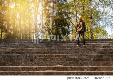 Man standing on the concrete stairs and looking to the forest trees Man standing on the concrete stairs and looking to the forest trees 102854086