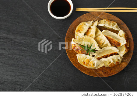 Gyoza Chinese Dumplings on Wood Plate, Fried Vegetable Jiaozi, Chicken Momo Pile, Asian Gyoza Group 102854203
