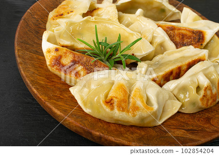 Gyoza Chinese Dumplings on Wood Plate, Fried Vegetable Jiaozi Macro, Chicken Momo Pile, Asian Gyoza Closeup 102854204
