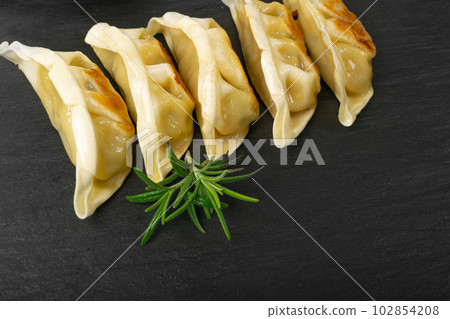 Gyoza Chinese Dumplings, Fried Vegetable Jiaozi, Chicken Momo Pile, Asian Gyoza Group on Black Stone Plate Gyoza Chinese Dumplings, Fried Vegetable Jiaozi, Chicken Momo Pile, Asian Gyoza Group on Black Stone Plate 102854208