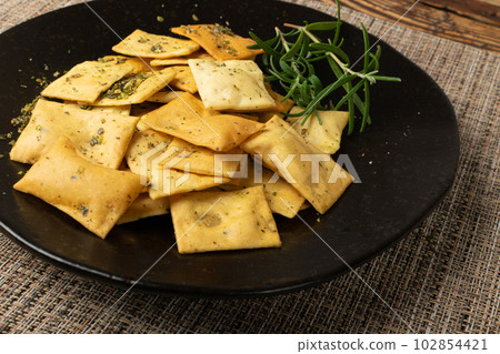 Pita Chips Pile on Black Plate, Small Wheat Tortillas, Crunchy Flat Bread, Spicy Mediterranean Wheat Snack 102854421