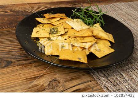 Pita Chips Pile on Black Plate, Small Wheat Tortillas, Crunchy Flat Bread, Spicy Mediterranean Wheat Snack 102854422