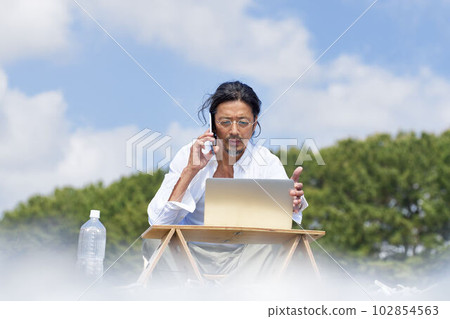 Man working on a PC outdoors Telework workation image Man working on a PC outdoors Telework workation image 102854563