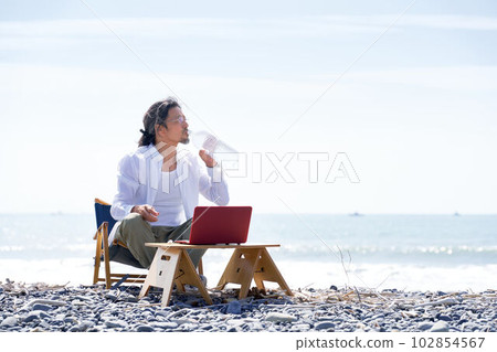 一個男人在沙灘上用桌椅放鬆 102854567