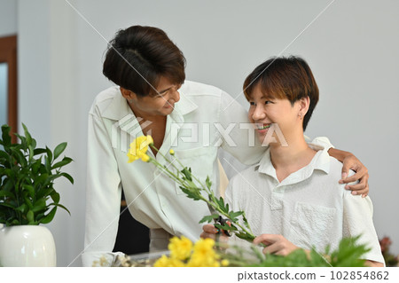 Affectionate romantic male gay couple spending time together, enjoying arranging flowers in cozy home. LGBT, homosexual and love Affectionate romantic male gay couple spending time together, enjoying arranging flowers in cozy home. LGBT, homosexual and love 102854862