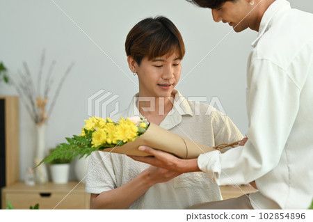 Loving young asian man giving a bunch of flowers to his boyfriend. LGBTQ people lifestyle and love emotion 102854896